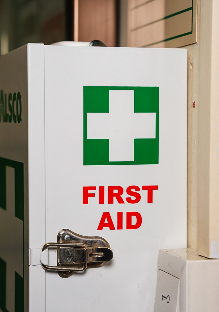 Wall-mounted Alsco first aid cabinet with a green cross, part of a managed first aid service