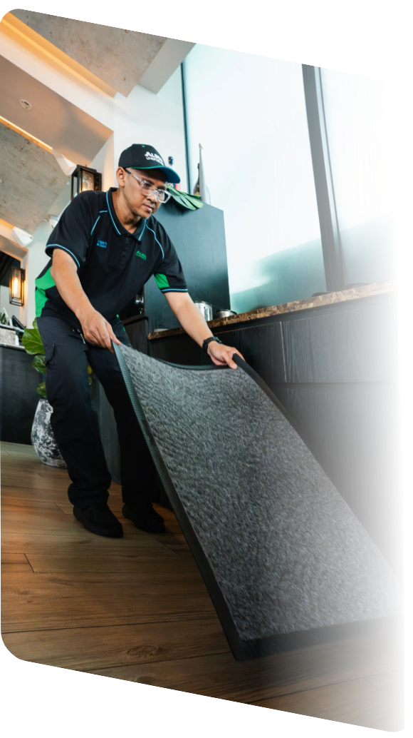 Alsco service technician laying a grey commercial floor mat inside a modern restaurant