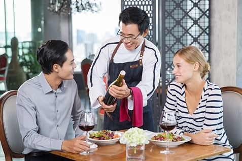 Asian waiter serving wine