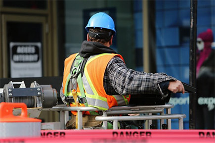 A construction man wearing a hi vis vest and a hard hat at work.
