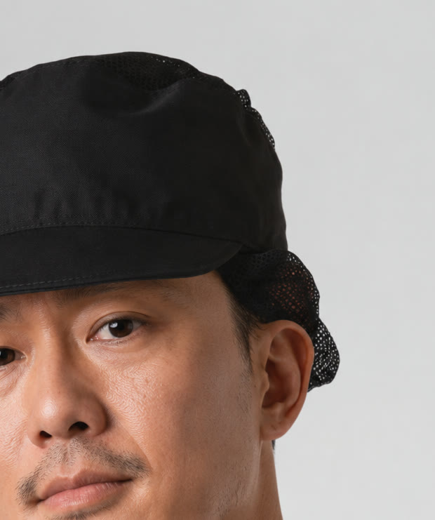 Close-up of a chef wearing a black Cutting Edge chef cap with a mesh back